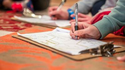 A close up of two children writing on clipboards